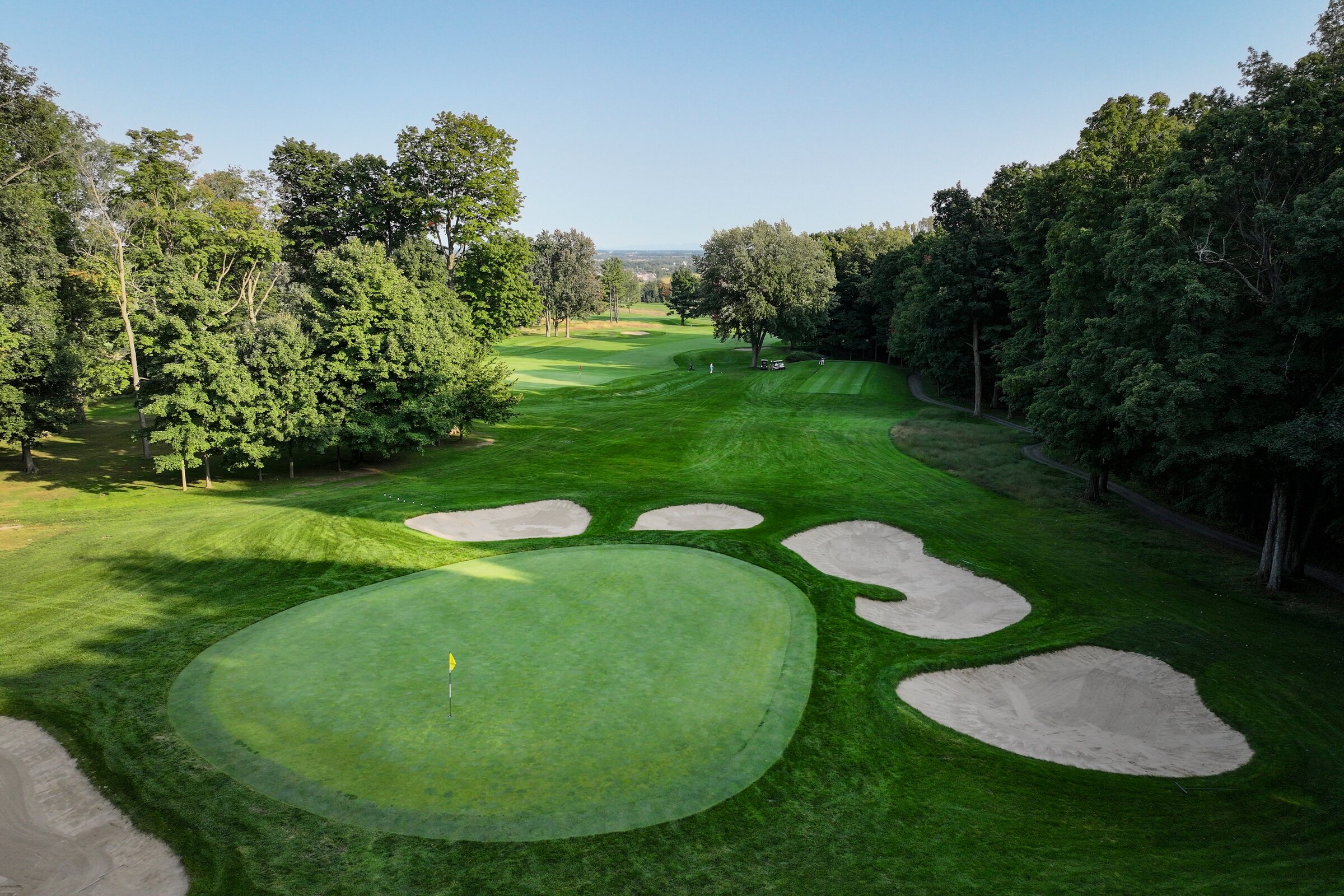 Green and bunkers surrounded by mature trees